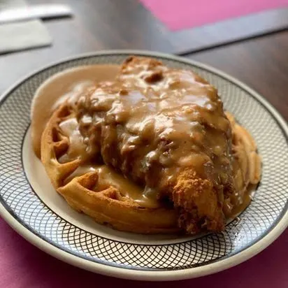 A plate of fried chicken and a waffle under gravy
